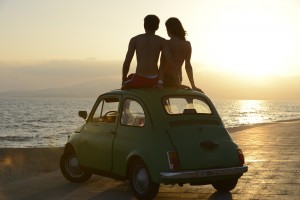 romantic vacation: couple at sundown on the beach with car